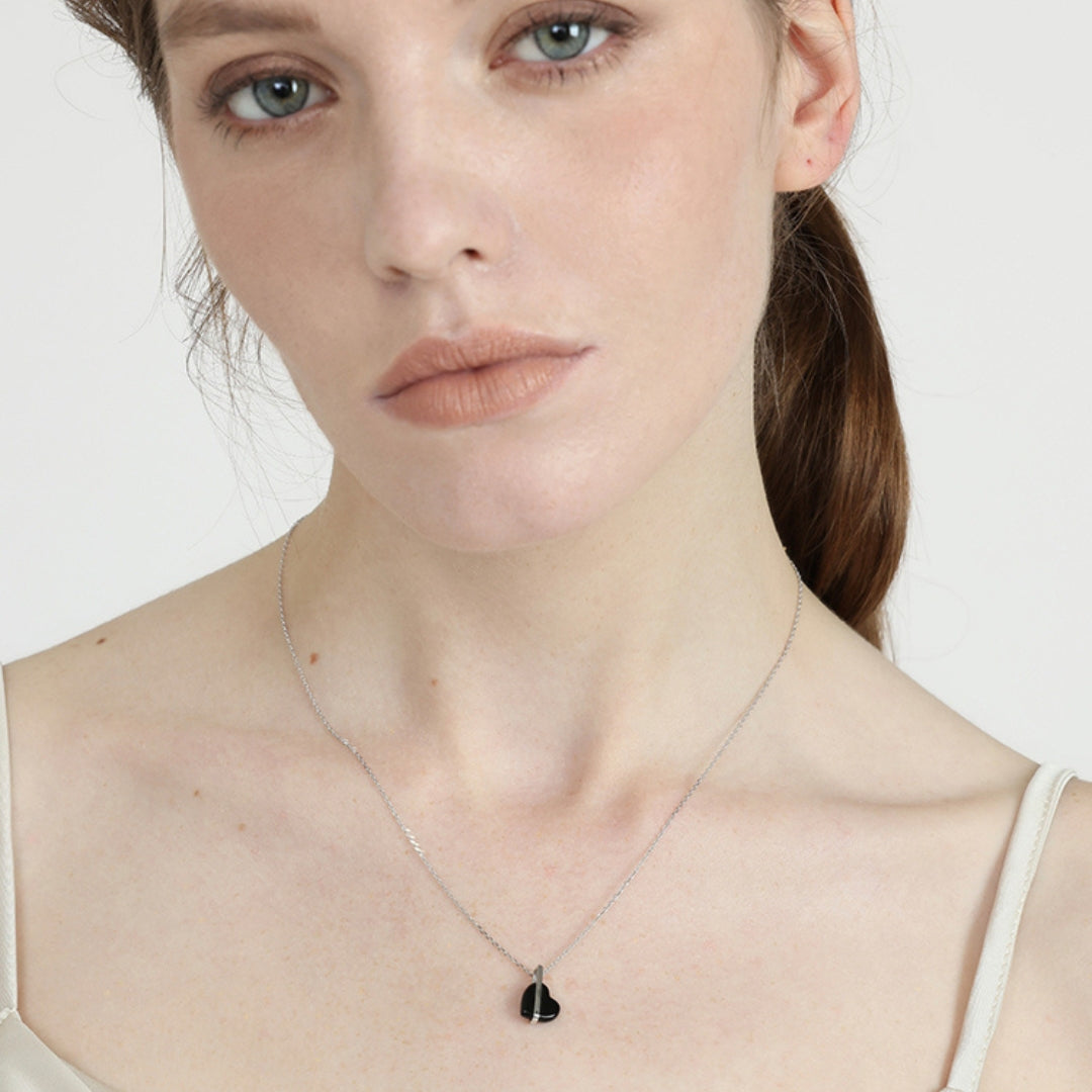 Woman wearing a 14k gold necklace with a black pendant made of black onyx on a white background