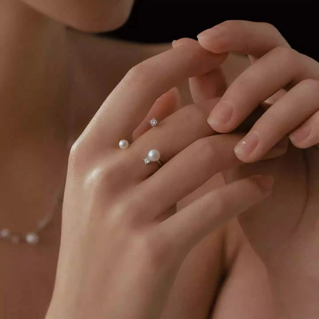 A profile shot of a woman looking down, emphasizing the clean lines of the wrap-around pearl earrings and the sophisticated glow of freshwater pearls.