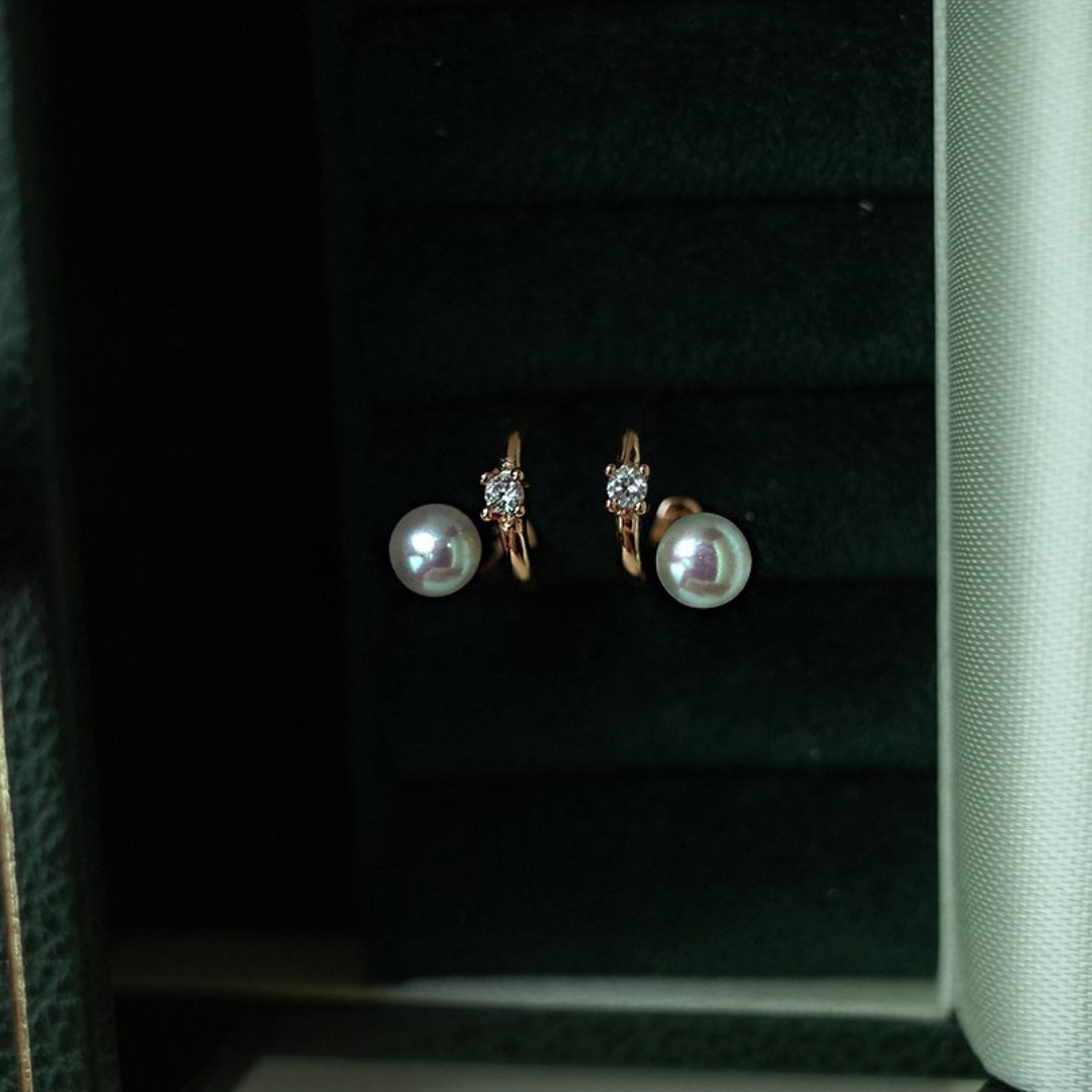 Pair of pearl earrings for wedding on a dark green fabric background