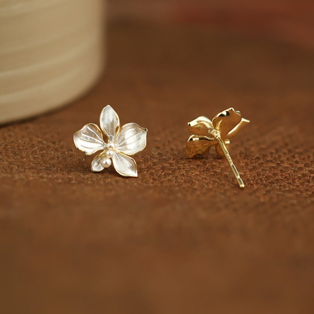 Sterling silver flower stud earrings on a brown surface