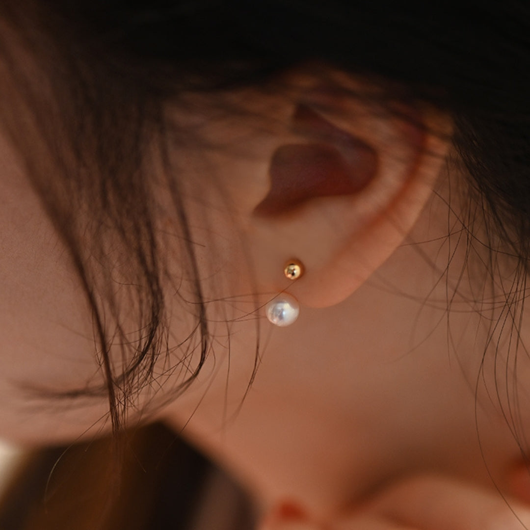 Close-up of an ear wearing a gold pearl earring.