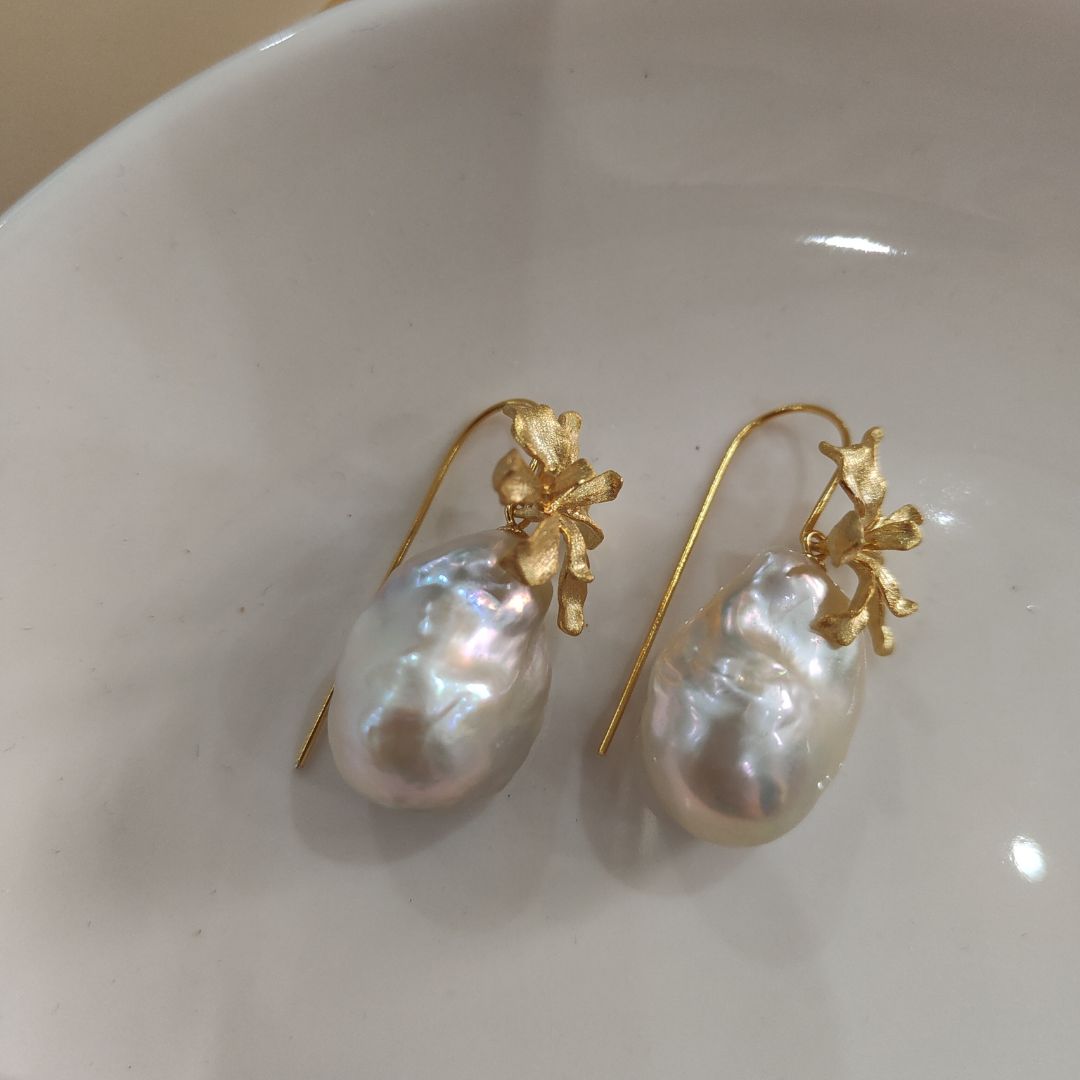 A pair of delicate gold iris flower pearl earrings with intricate flower detailing, symbolizing wisdom and hope, paired with lustrous Freshwater Cultured Pearls, ideal for a wedding or formal event.