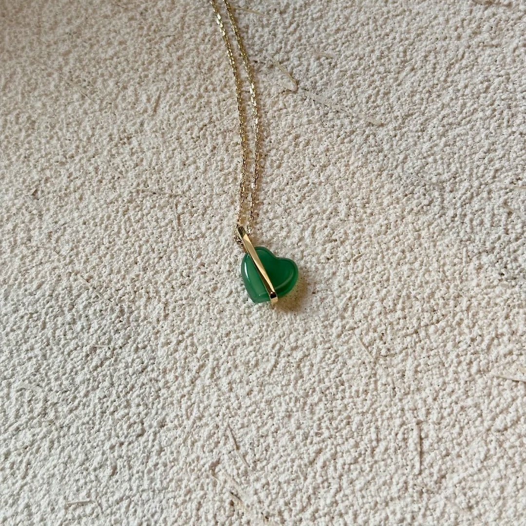 Necklace with a green heart-shaped pendant on a beige carpet