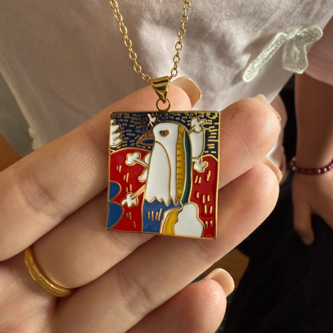 Colorful pendant with a bird design held by a hand