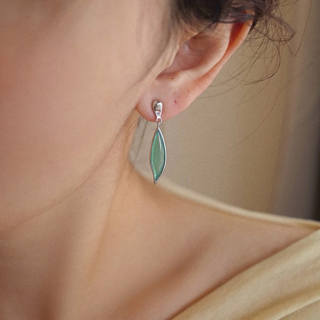 Close-up of a person wearing a green leaf earring.