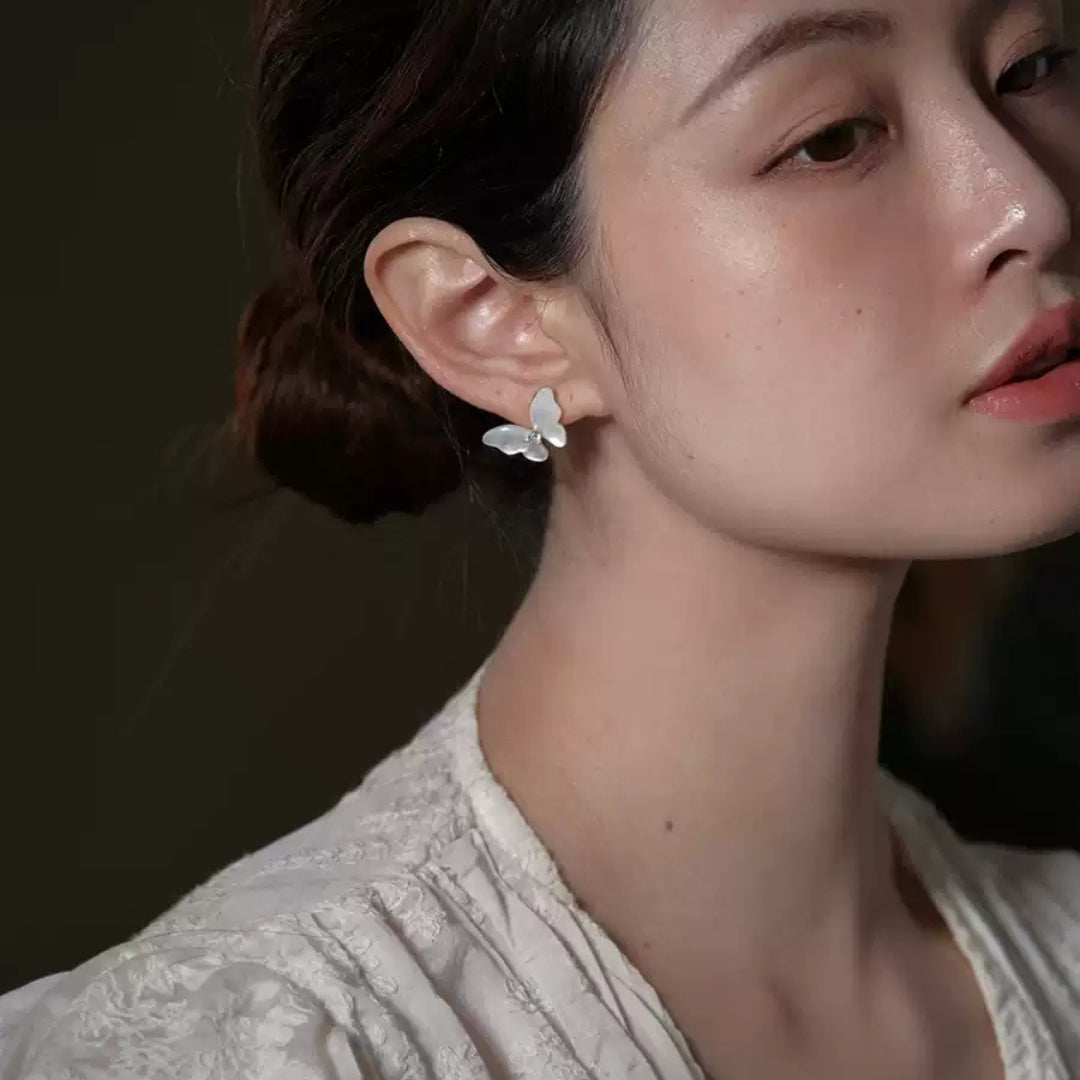 Close-up of a woman wearing a butterfly earring with a dark background