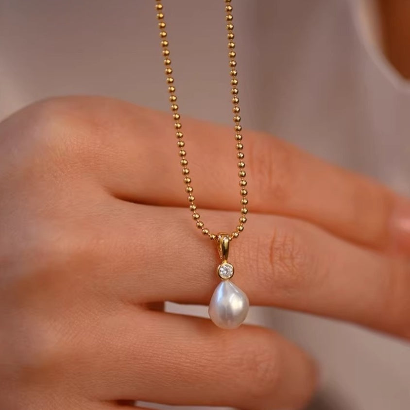Detail shot of lustrous white teardrop pearl pendants hanging from delicate gold ball chains, showing the organic baroque shape. 7