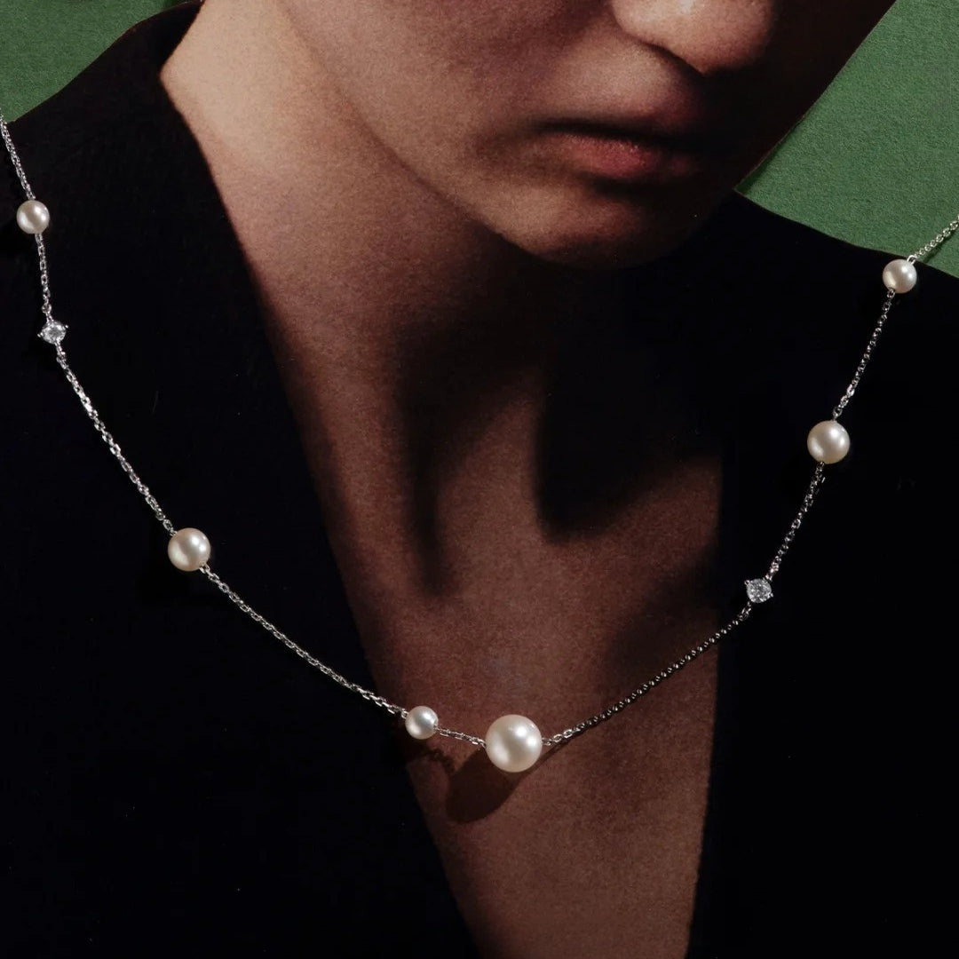Cultured freshwater pearl necklace worn by a person against a dark background
