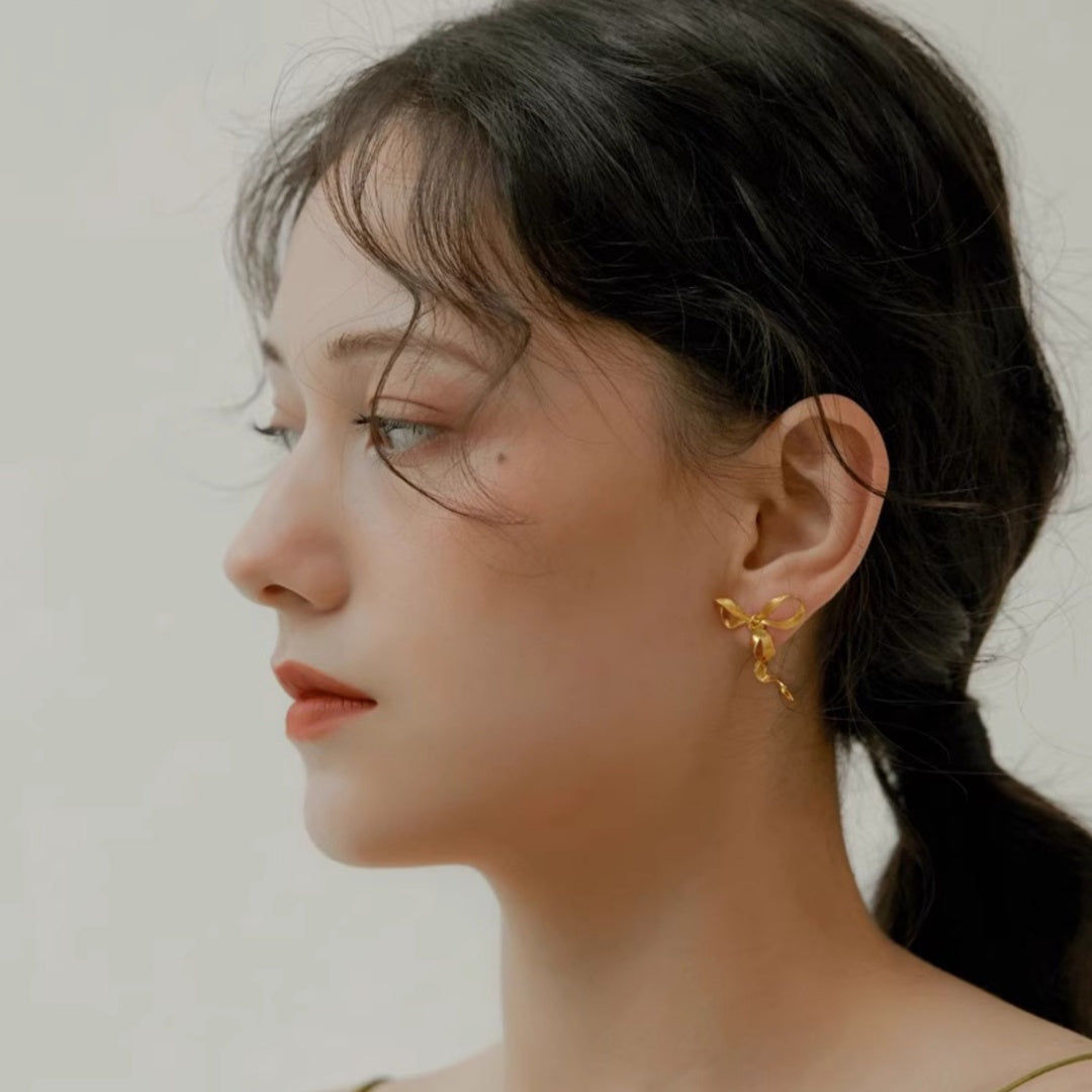 Front view of model wearing Sculptural Ribbon Bow gold earrings for elegant facial framing - model-look-3