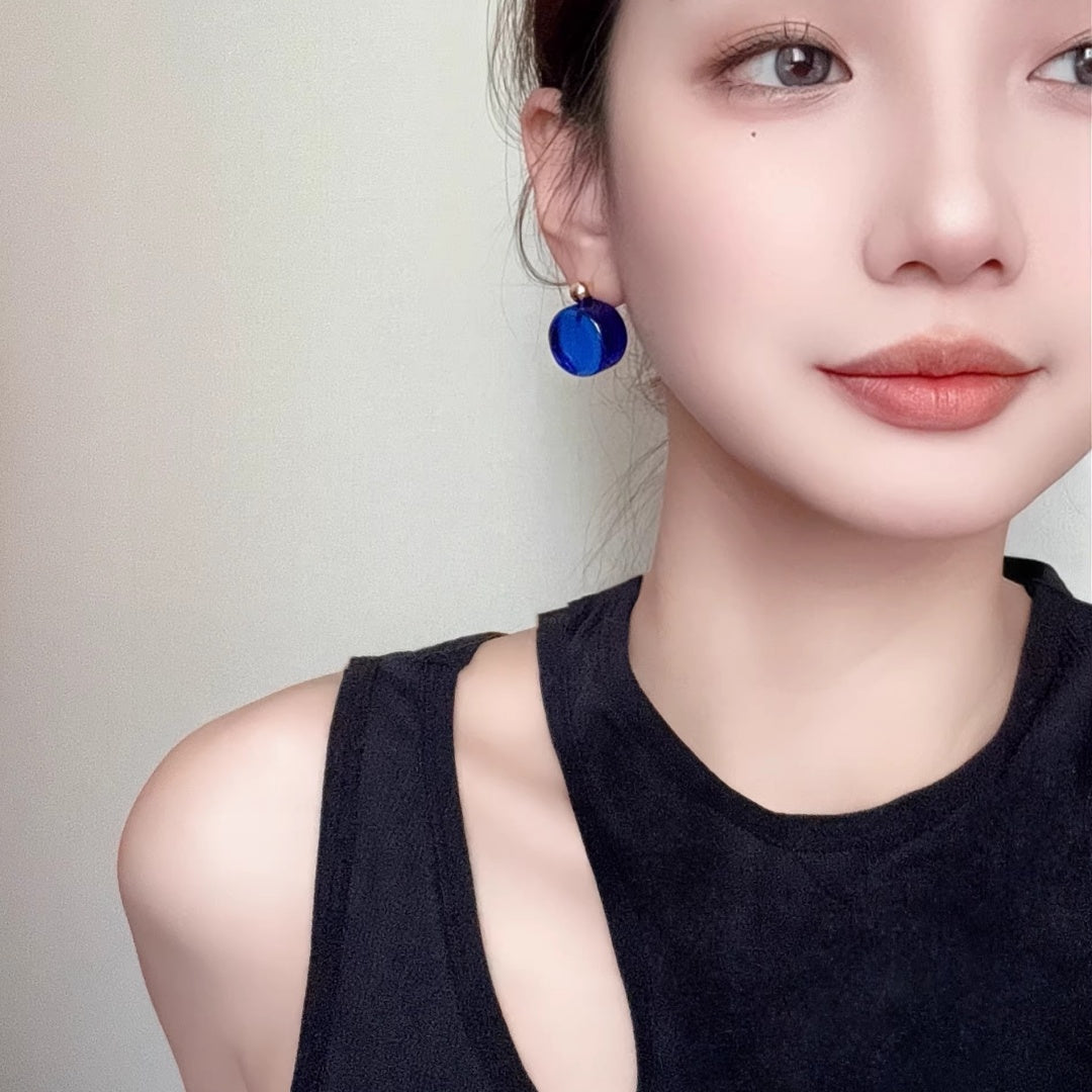 Close-up of a model wearing the deep blue glass stud earrings, showcasing size and scale.