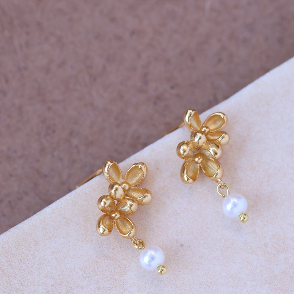 Close-up shot showing the matte texture of 18k gold flower petals and the luster of a natural freshwater pearl -3