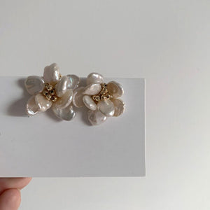 A pair of handcrafted pearl flower stud earrings featuring baroque freshwater pearls and gold bead accents in the center. These dainty pearl flower earrings are perfect bridal flower earrings and floral wedding earrings, making them an elegant choice for statement wedding bridal jewelry.