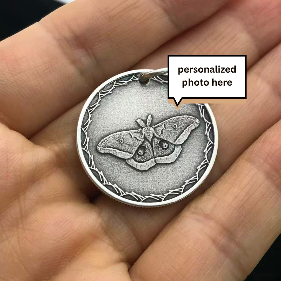 Silver pendant with butterfly design held in a hand