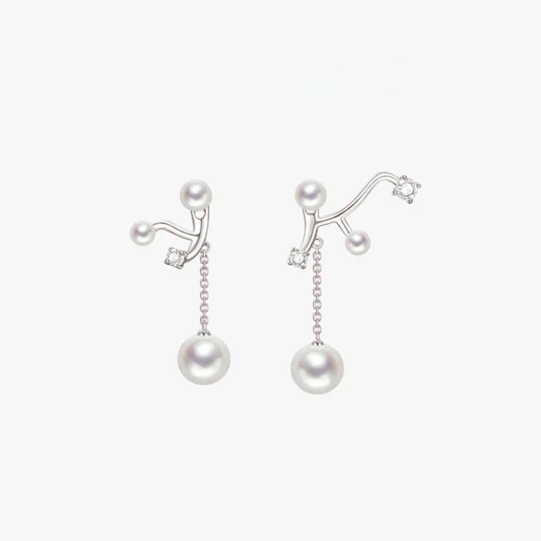 A pair of silver branch-shaped dangle earrings with white freshwater pearls and small clear cubic zirconia accents, shown on a light gray background.
