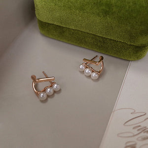 Close-up of gold bar pearl earrings featuring Tiny pearl studs arranged in a trio on Gold bar earring studs, perfect as Minimalist Wedding Earrings and Dainty elegant earrings for everyday wear.