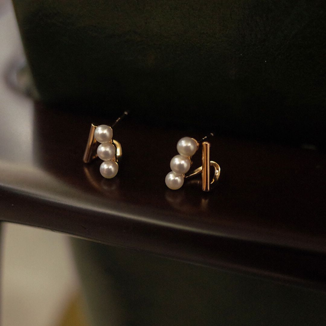 Close-up of gold bar pearl earrings featuring Tiny pearl studs arranged in a trio on Gold bar earring studs, perfect as Minimalist Wedding Earrings and Dainty elegant earrings for everyday wear.