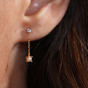 Close-up of tiny pearl and diamond short chain earrings in gold, featuring natural freshwater pearls and diamonds; elegant bridal jewelery or daily wear.