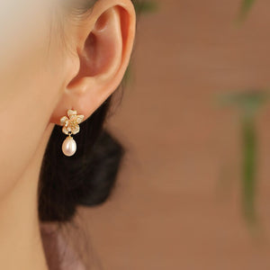 Close-up of gold sakura charm earrings featuring pink petals and pearls, designed as sakura pearl earrings and Flower Stud Earrings—perfect for Cottage core earrings and Cherry Blossom Earrings styles.