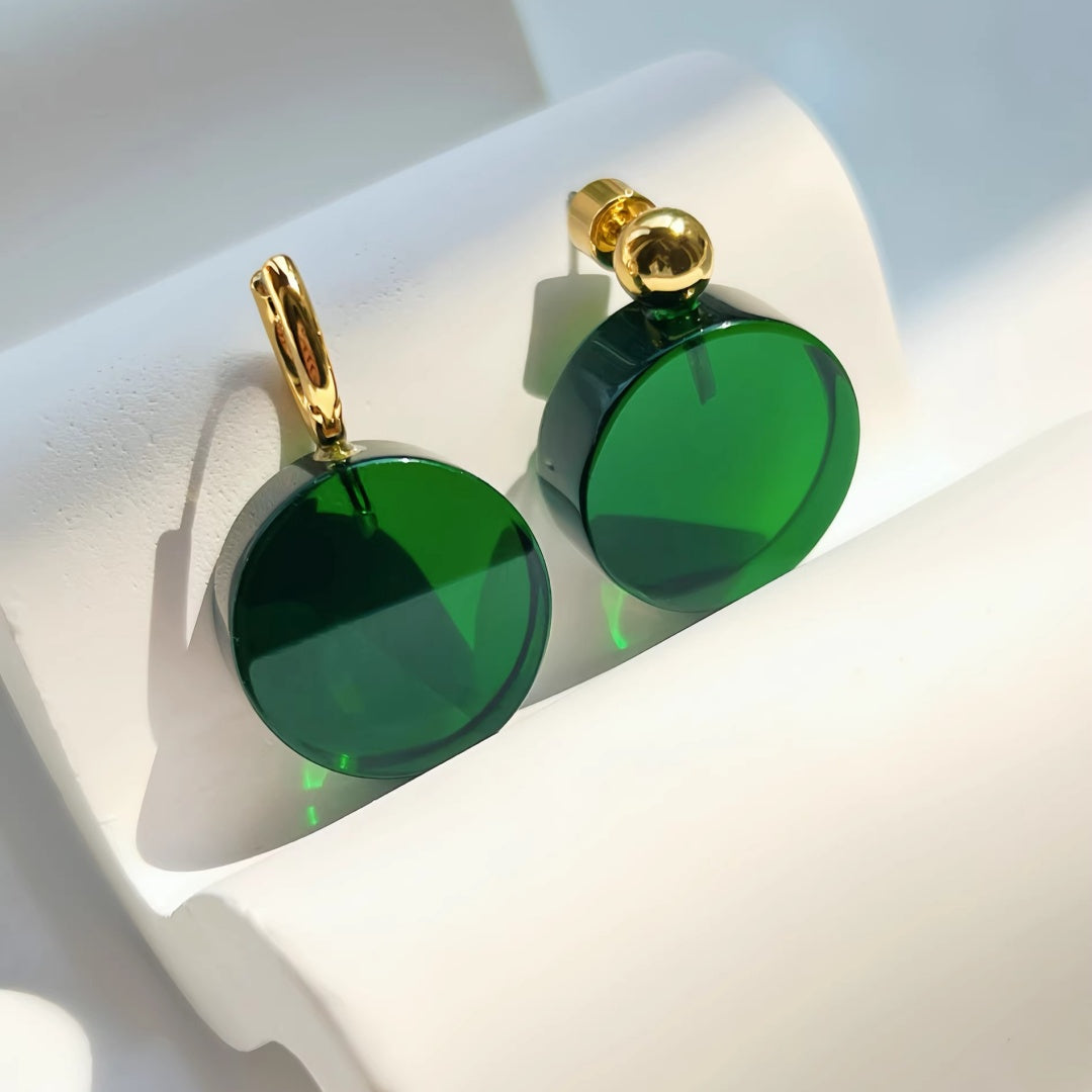 High-quality emerald green glass circular earrings with thick 18K gold plating on a modern white backdrop.