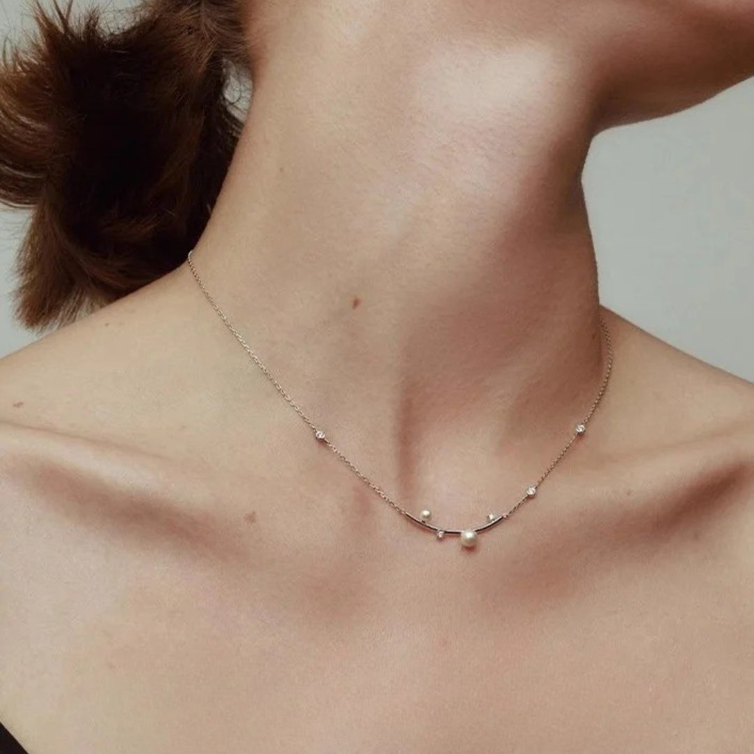 A silver diamond and pearl necklace wore by a woman. 