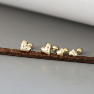 A pair of tiny gold heart studs with a delicate, minimalist design. These gold heart stud earrings showcase a classic Korean jewelry style, perfect for everyday wear.