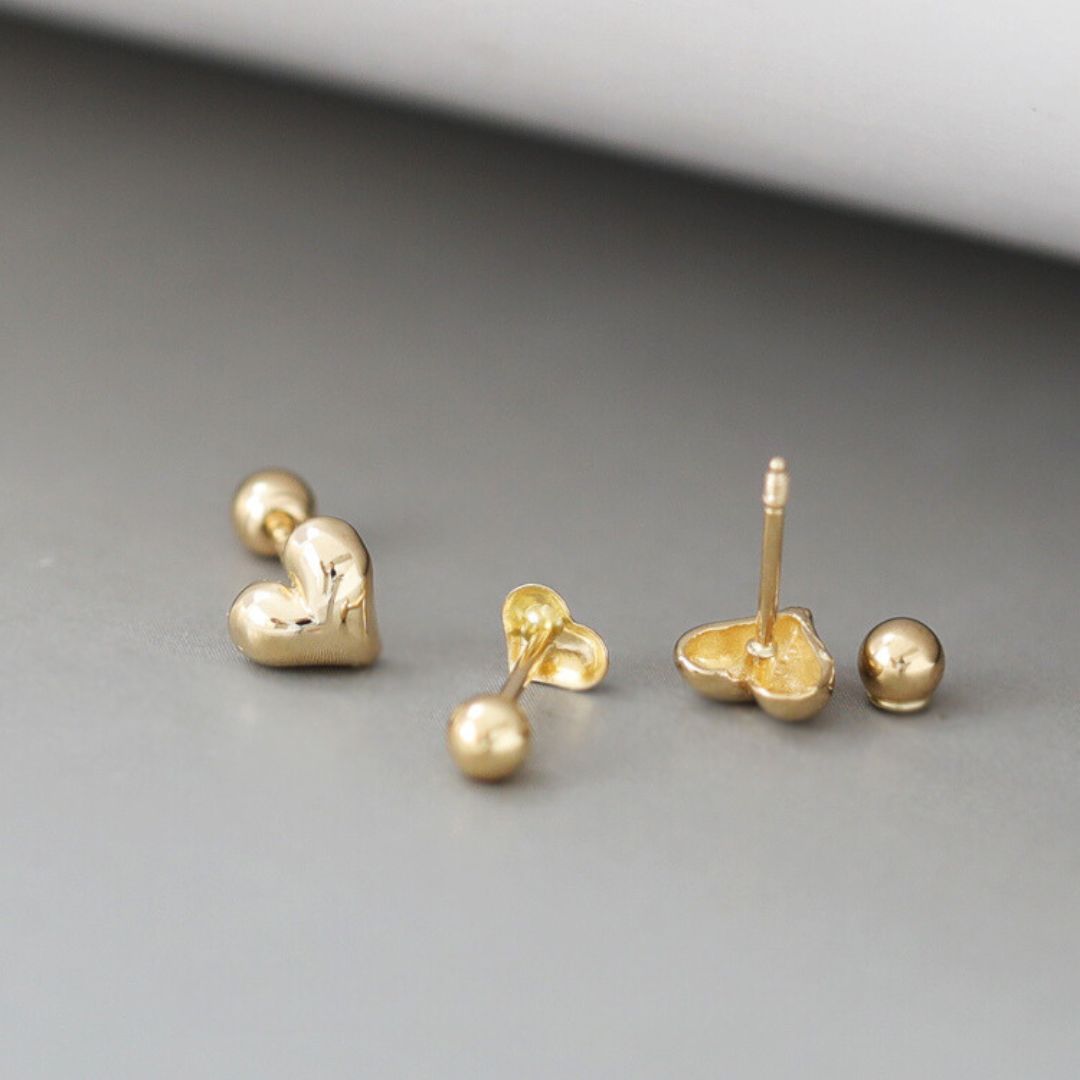 A pair of tiny gold heart studs with a delicate, minimalist design. These gold heart stud earrings showcase a classic Korean jewelry style, perfect for everyday wear.