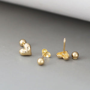 A pair of tiny gold heart studs with a delicate, minimalist design. These gold heart stud earrings showcase a classic Korean jewelry style, perfect for everyday wear.