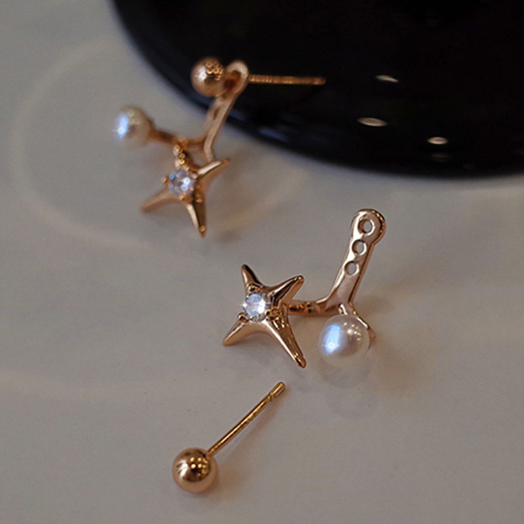 Dainty gold star stud earrings featuring a starburst design with a freshwater pearl, combining celestial elegance with vintage charm.