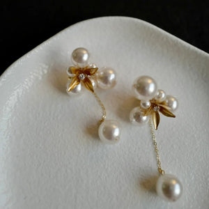 A pair of handcrafted vintage pearl flower earrings with a central gold flower surrounded by delicate pearls. The earrings feature a removable dangle, allowing them to be worn as pearl flower stud earrings or pearl cluster drop earrings. Perfect for brides, these dainty pearl flower earrings are ideal for floral wedding earrings or bridal flower earrings, offering versatile statement wedding bridal jewelry.