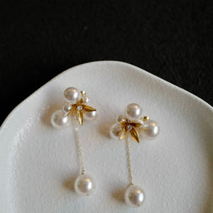 A pair of handcrafted vintage pearl flower earrings with a central gold flower surrounded by delicate pearls. The earrings feature a removable dangle, allowing them to be worn as pearl flower stud earrings or pearl cluster drop earrings. Perfect for brides, these dainty pearl flower earrings are ideal for floral wedding earrings or bridal flower earrings, offering versatile statement wedding bridal jewelry.