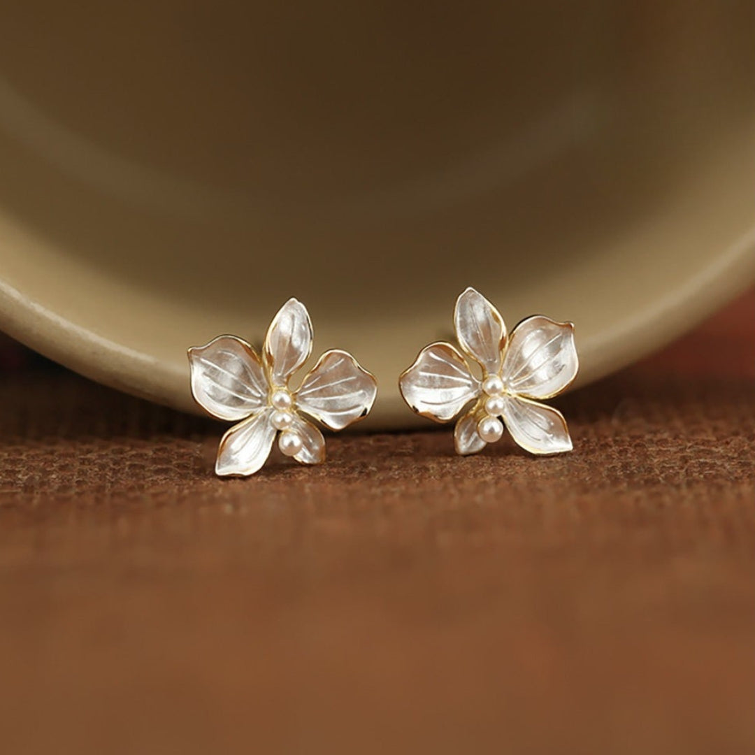Pair of white flower earrings on a wooden surface with a blurred background