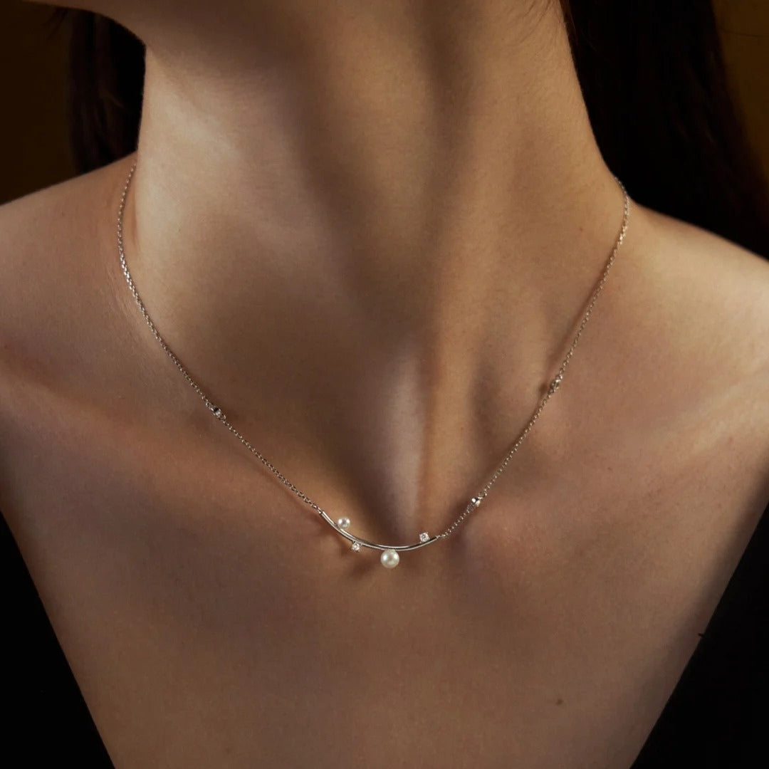 A close up for a pearl and diamond necklace wore by a woman.