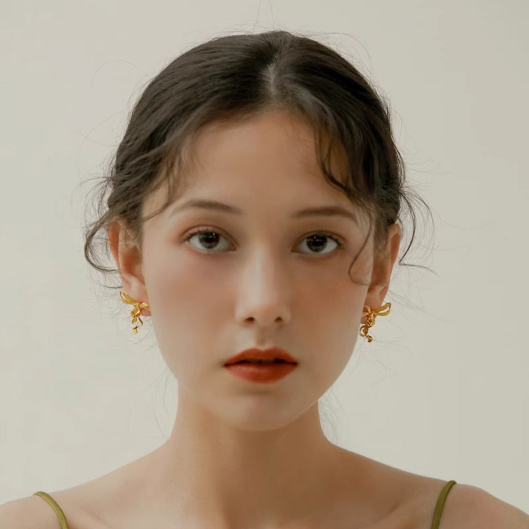 Front view of model wearing Sculptural Ribbon Bow gold earrings for elegant facial framing - model-look-4