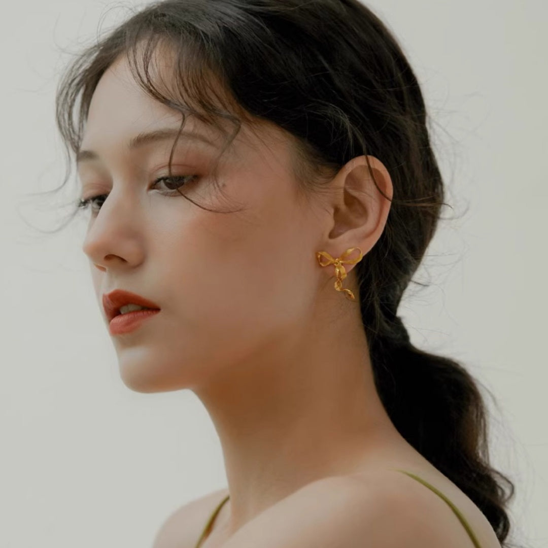Front view of model wearing Sculptural Ribbon Bow gold earrings for elegant facial framing - model-look-1