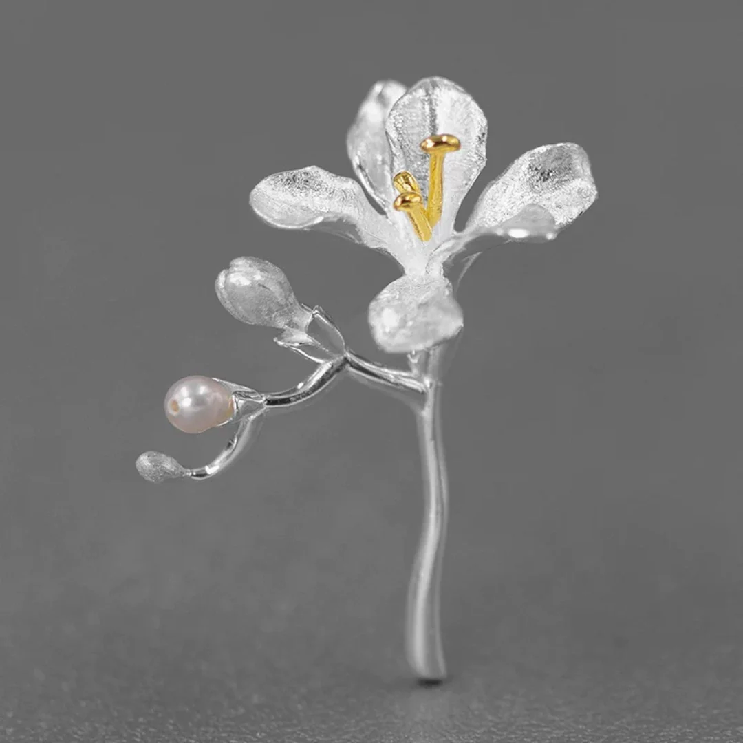 Minimalist freesia branch pin handcrafted in silver with freshwater pearl - Studio product shot.