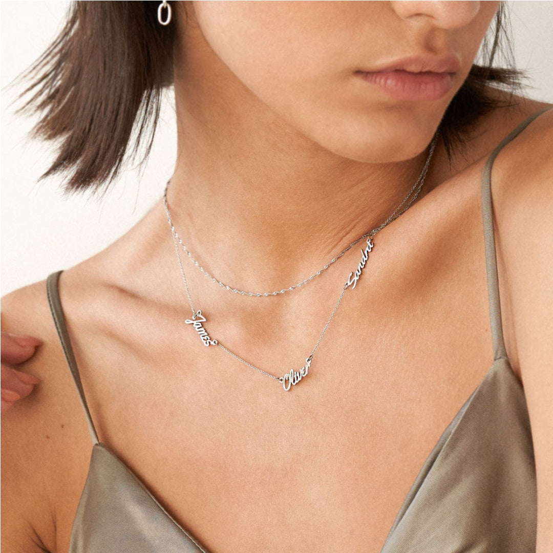 Elegant woman wearing an asymmetric 3 name necklace in sterling silver, a perfect personalised gift for mothers. 3