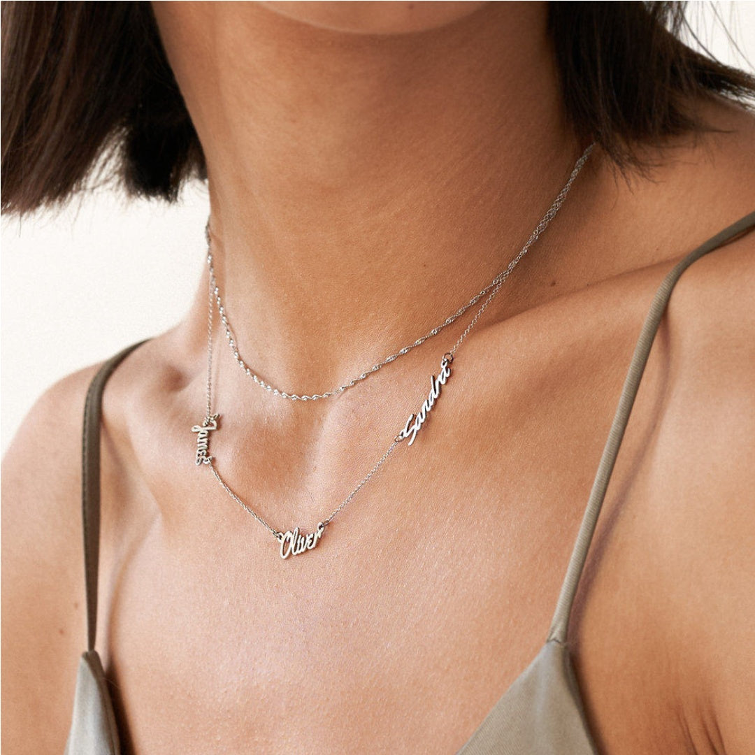 Elegant woman wearing an asymmetric 3 name necklace in sterling silver, a perfect personalised gift for mothers. 2