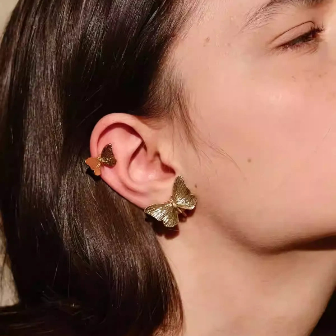 Close up of gold butterfly stud and ear cuff styling on model's ear.